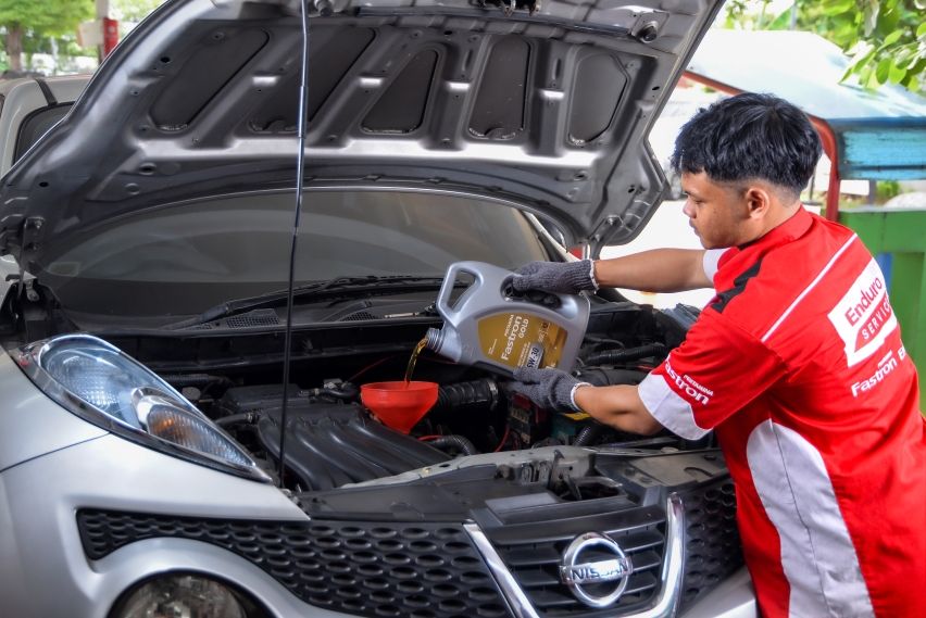 Mekanik Enduro Service di SPBU Pertamina sedang mengganti oli mobil